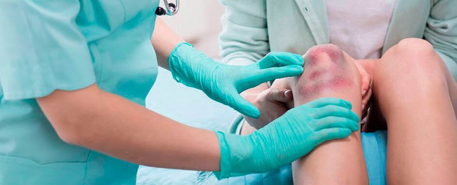 Un médico examina una lesión en la rodilla.